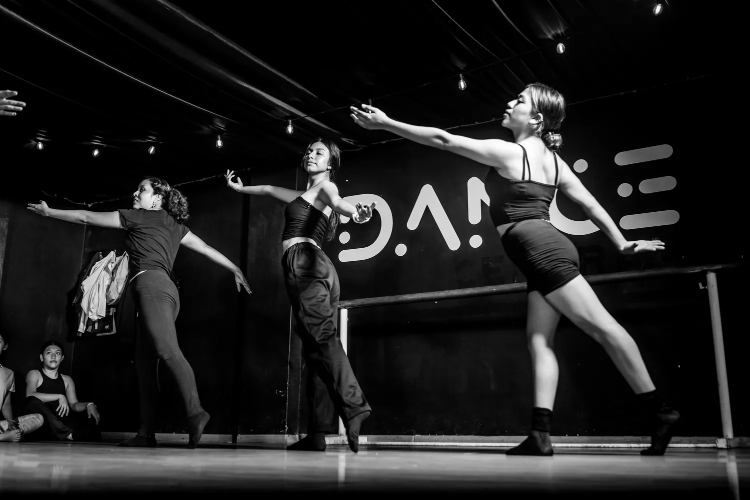 Tres bailarinas de Dance Central ensayando una secuencia en el salón, con el logotipo del estudio al fondo